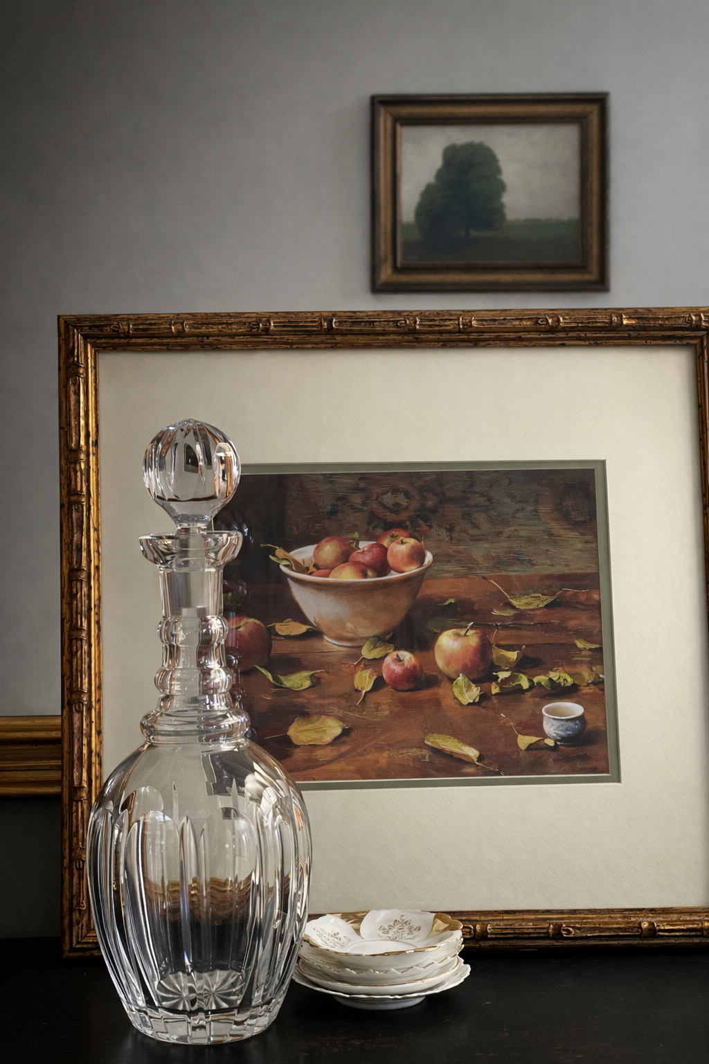 Clear glass decanter on a table with framed artwork in the background