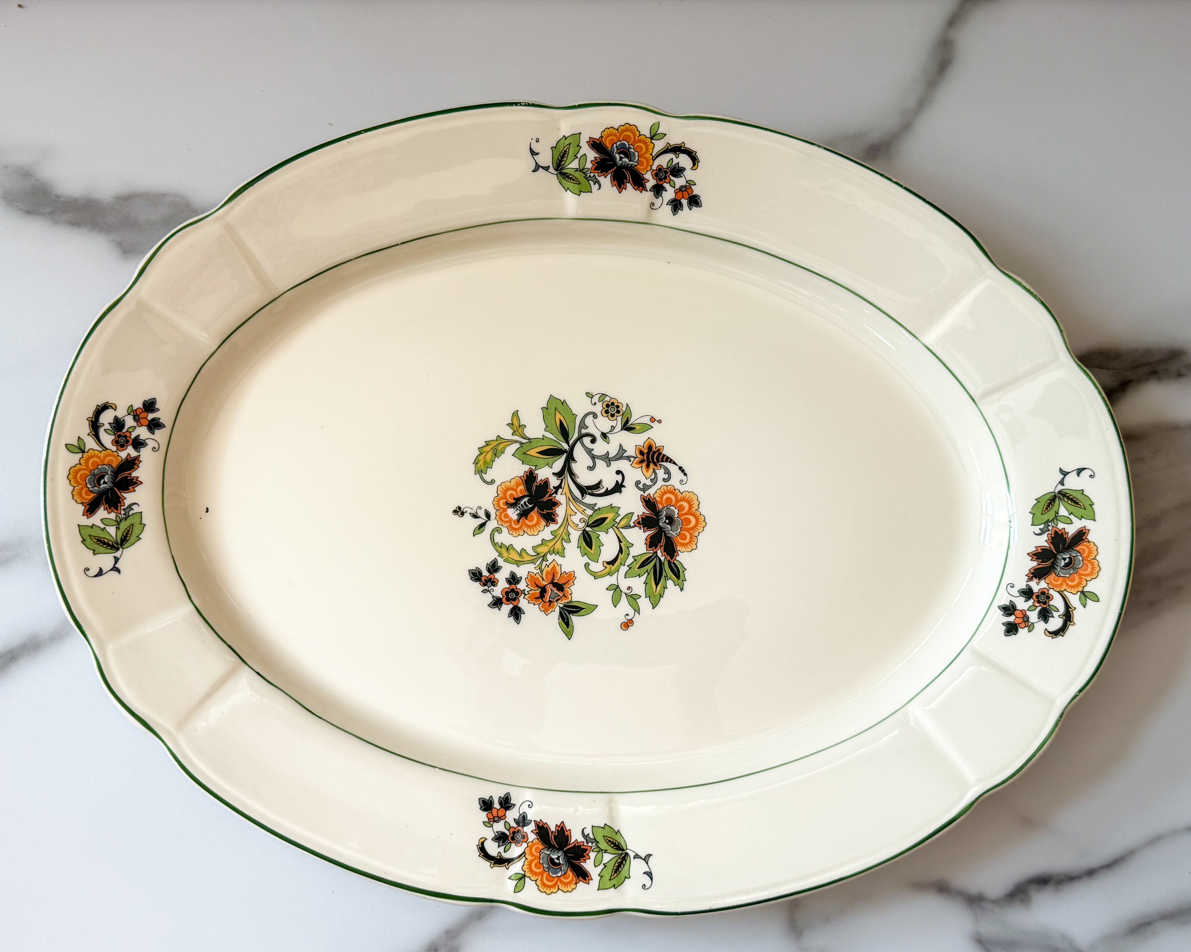 Vintage platter with a subtle scalloped edge and a delicate floral spray pattern.