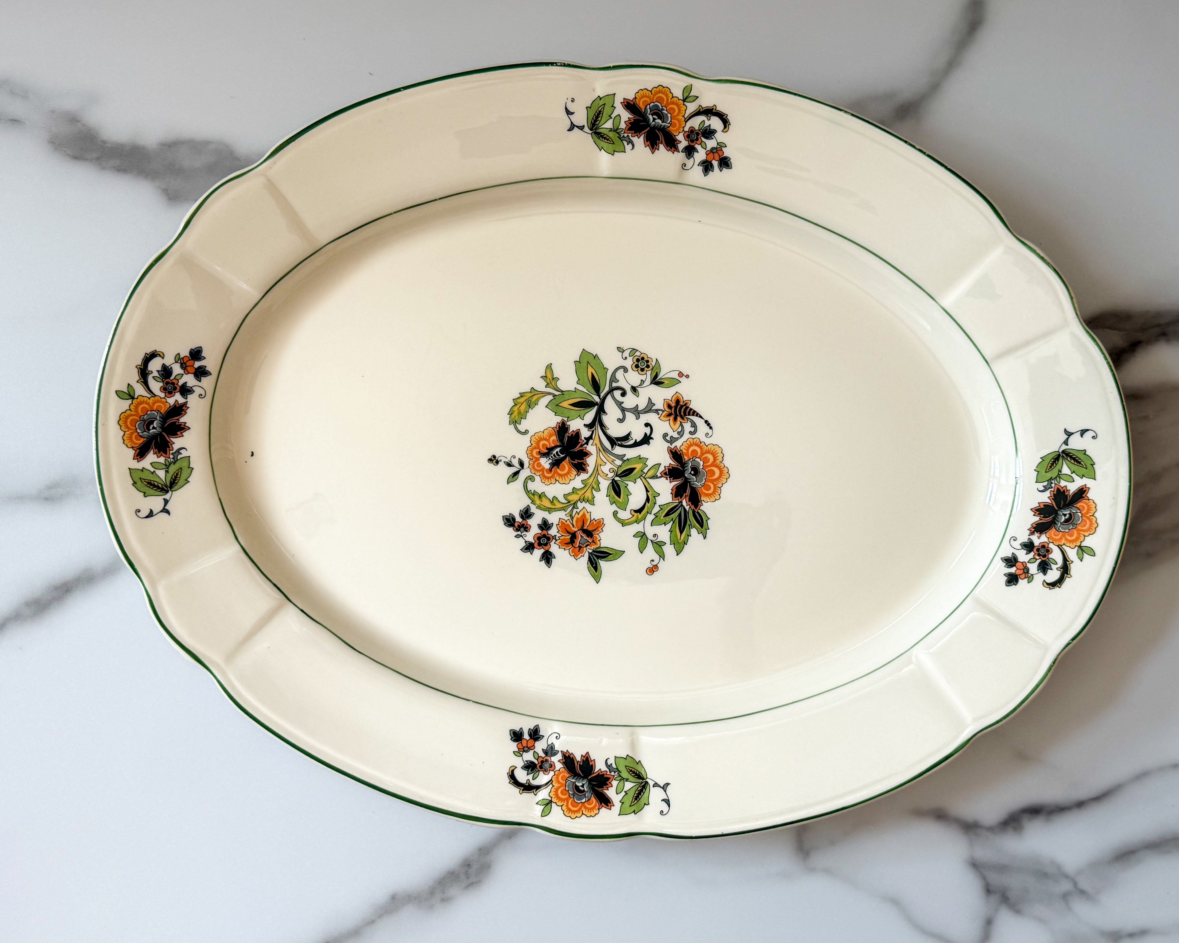 Vintage platter with a subtle scalloped edge and a delicate floral spray pattern.