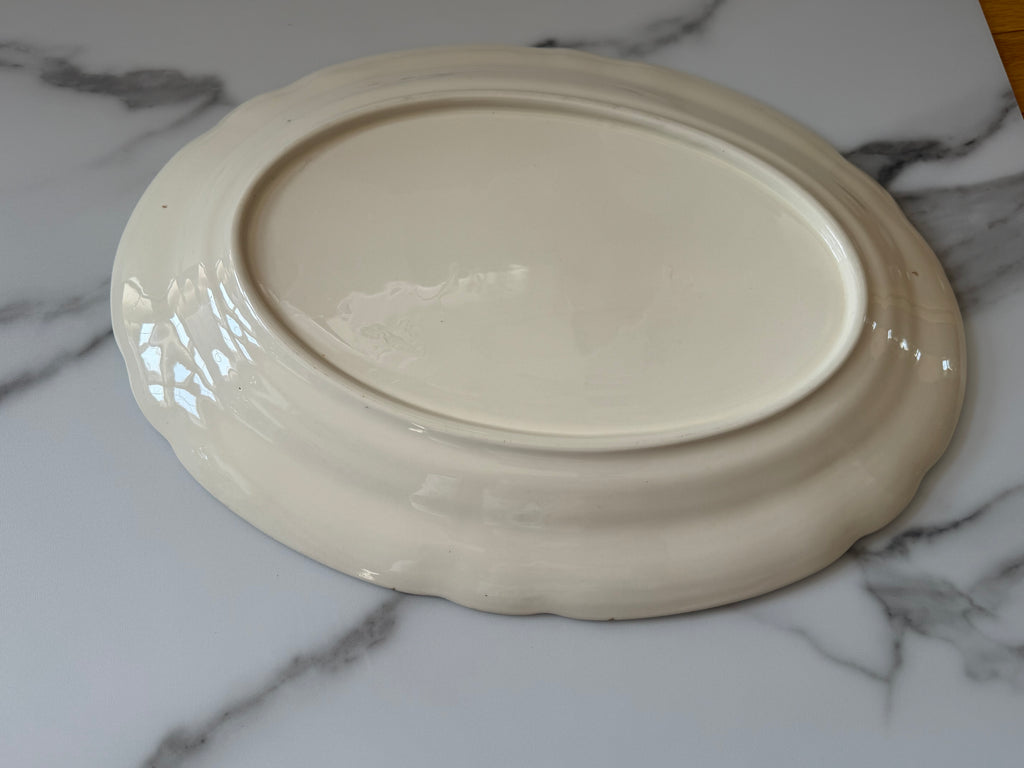 Vintage platter with a subtle scalloped edge and a delicate floral spray pattern.