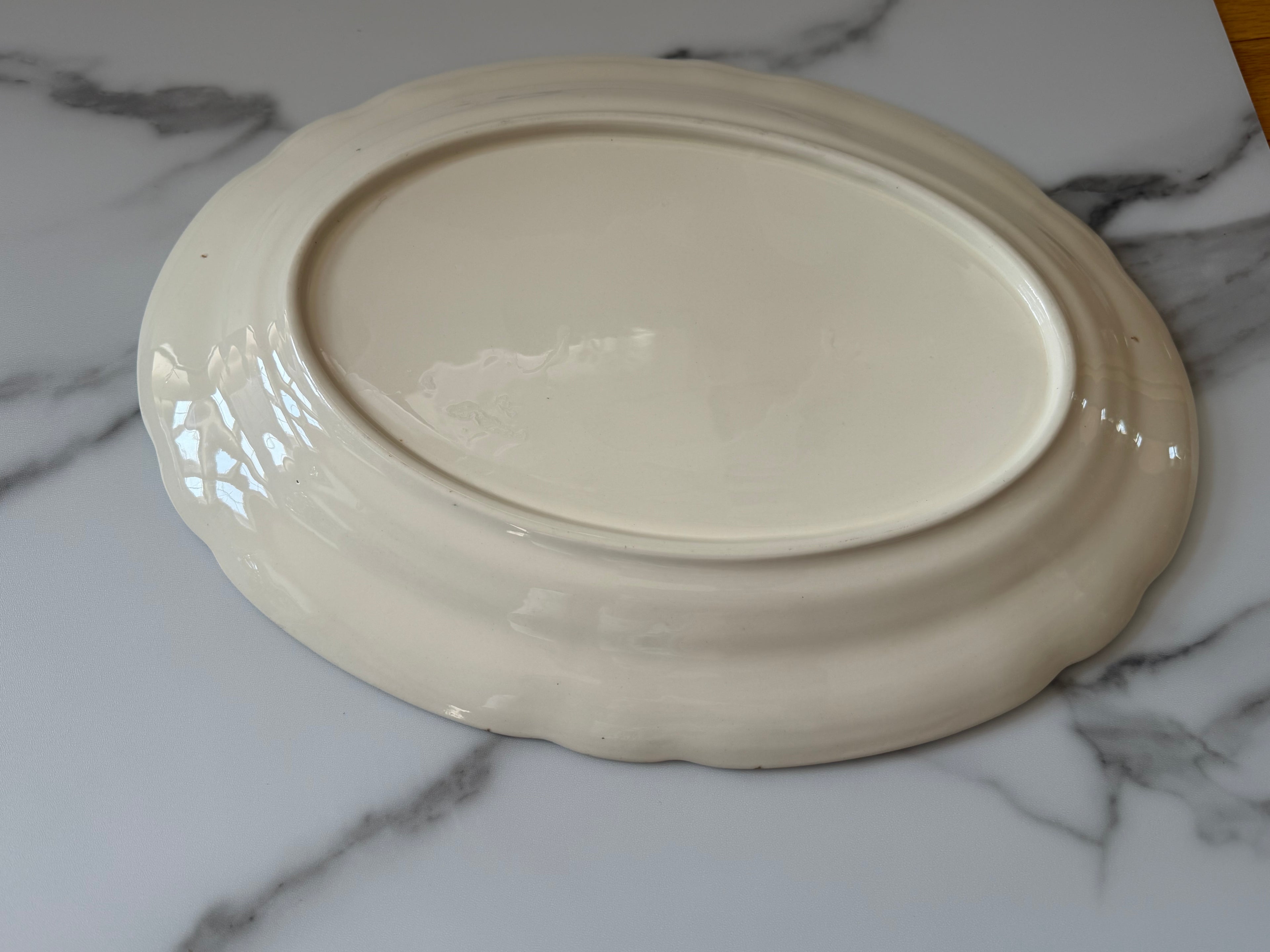 Vintage platter with a subtle scalloped edge and a delicate floral spray pattern.
