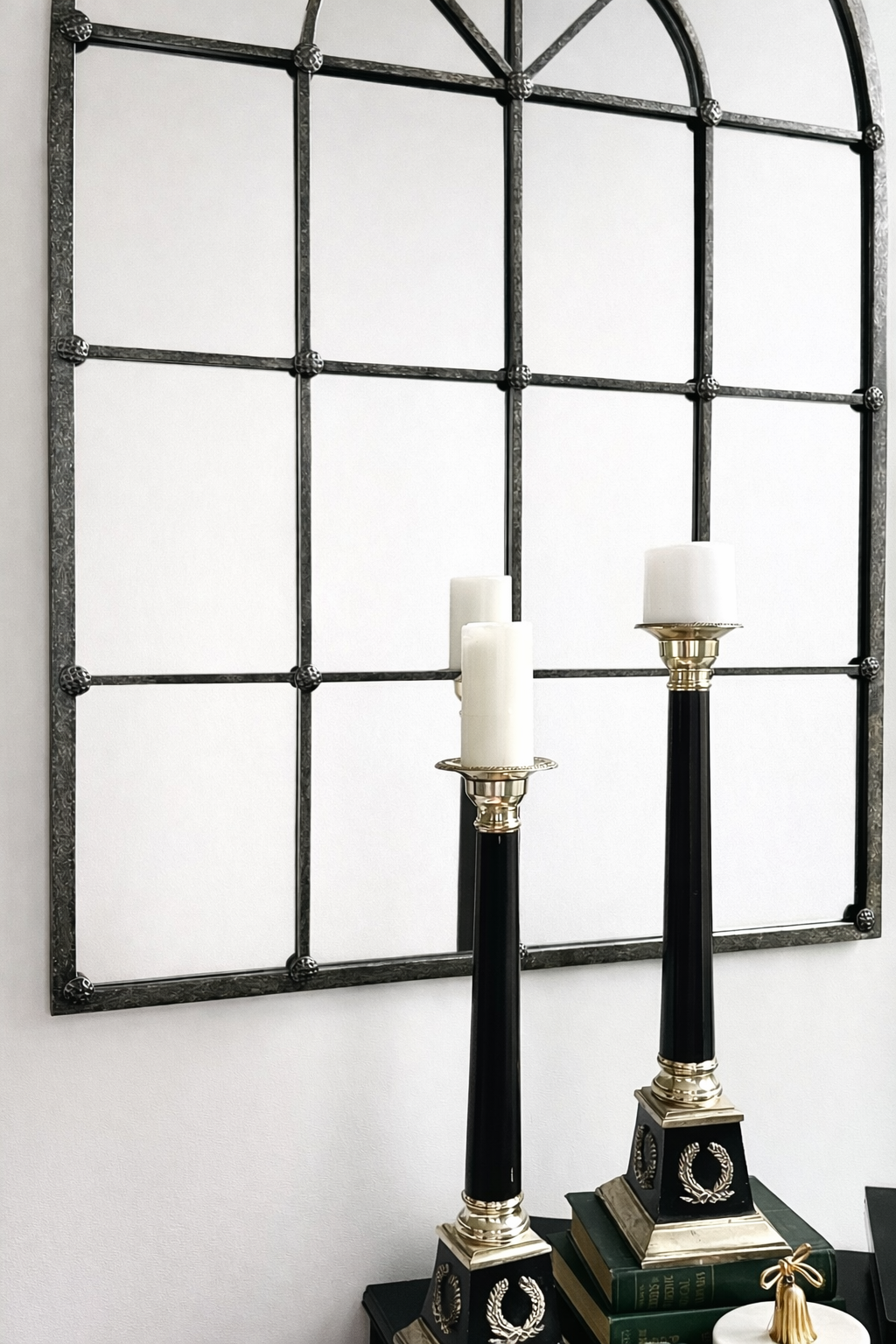 Decorative wall mirror with black frame and two candle holders in front.